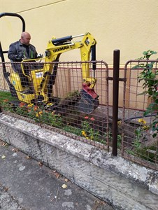 Mikrobagr pracuje u plotu za zídkou